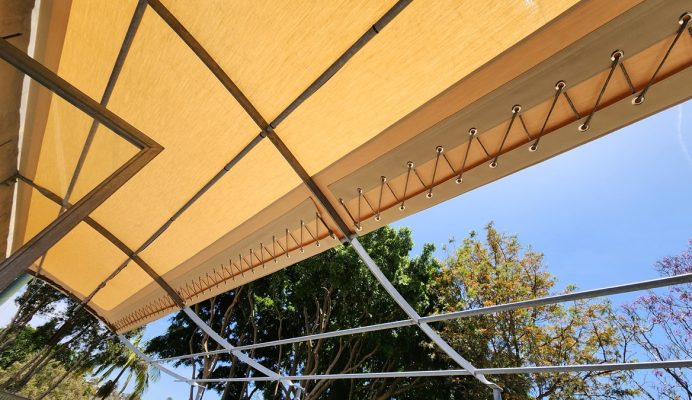 An awning hanging over a patio with trees in the background.