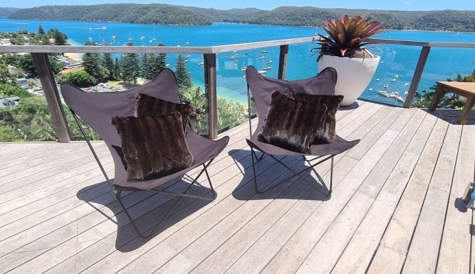 Two black chairs with custom made cushions on a deck overlooking the sea