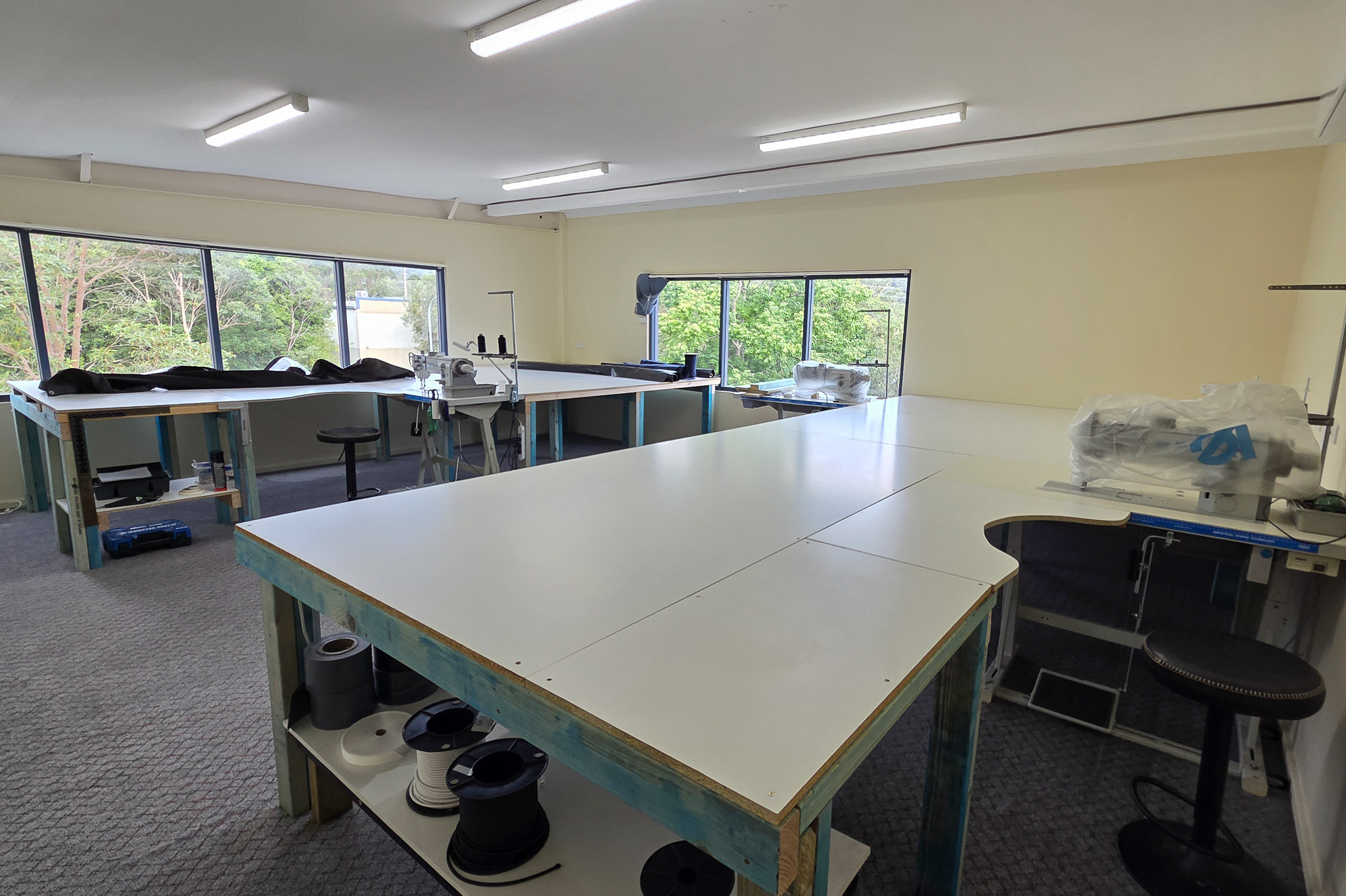 Ocean Covers upstairs sewing studio with industrial sewing machines, cutting tables and large windows overlooking trees