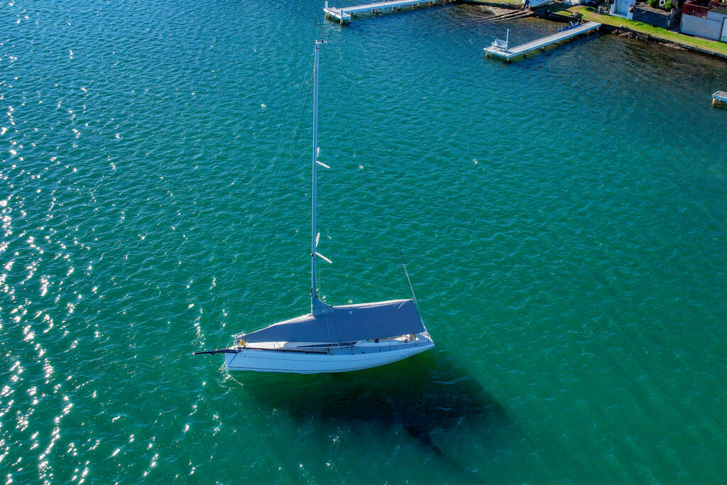 Overall protection cover — overhead drone view, Italia Yachts 9.98, Lake Macquarie Overhead aerial drone view of an Italia Yachts 9.98 Bellissima on a mooring in Lake Macquarie fitted with a custom grey WeatherMax overall protection cover by Ocean Covers, turquoise water with boat shadow visible below