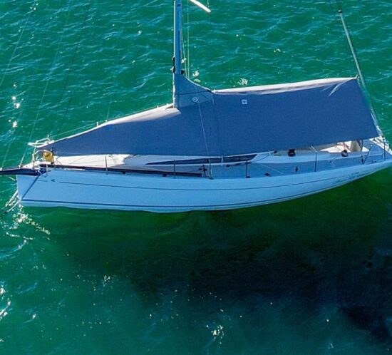 Overhead aerial drone view of an Italia Yachts 9.98 Bellissima on a mooring in Lake Macquarie fitted with a custom grey WeatherMax overall protection cover by Ocean Covers, turquoise water